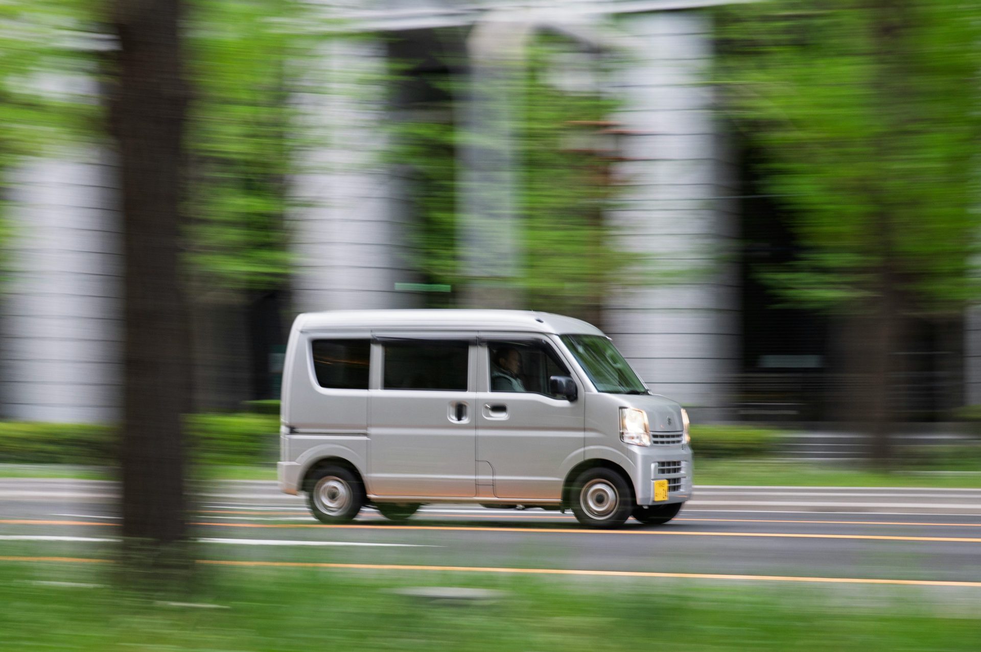 A silver van drives down a blurred street.